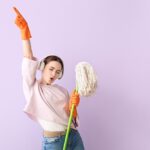Young,Woman,With,Floor,Mop,Listening,To,Music,On,Color